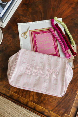 Pink Needlepoint XL Project Pouch holding embroidery yarns and essentials for crafting projects.