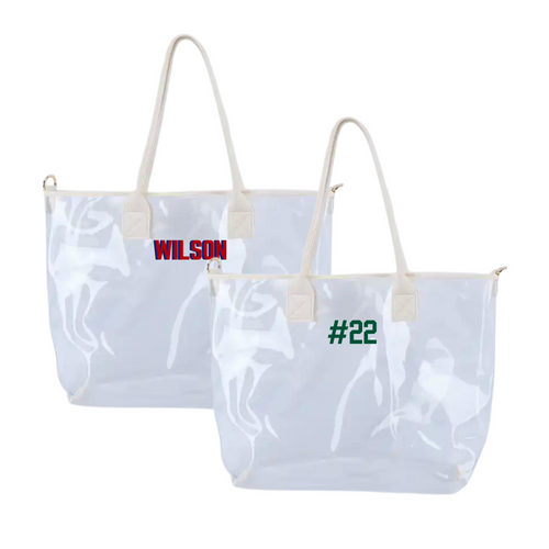 Two clear vinyl tote bags with cream handles, embroidered with red “WILSON” and green “#22.”