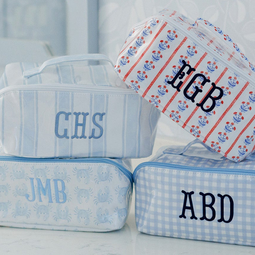 Set of personalized toiletry bags with monograms on a bathroom counter.