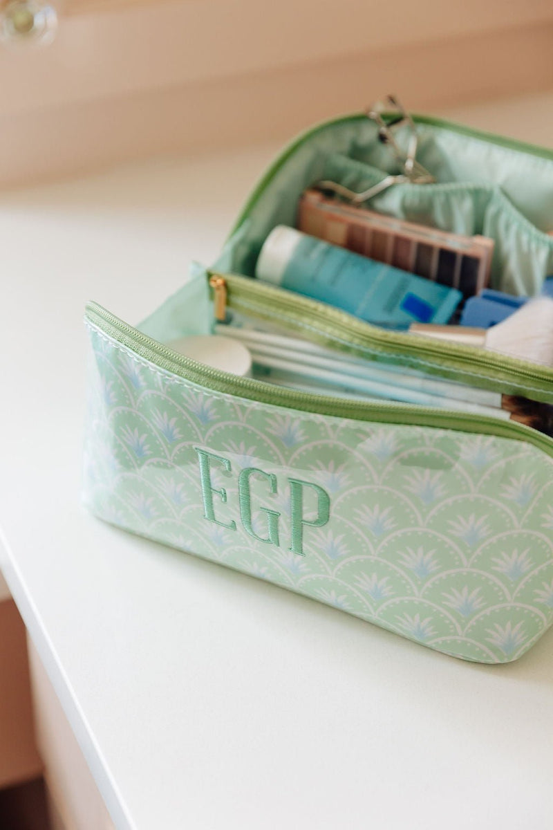An open green fan-print clear-coated pouch monogrammed 'EGP' with makeup organized inside