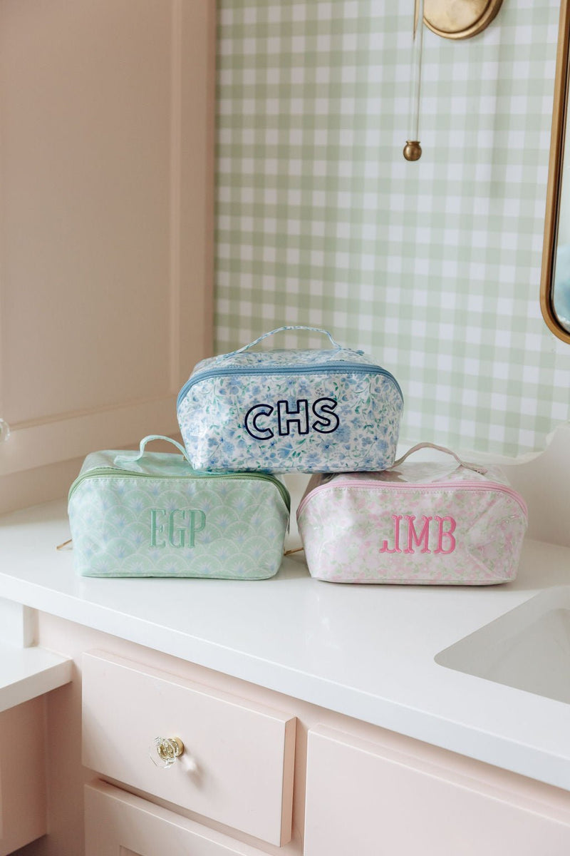 Three clear-coated flat lay pouches monogrammed CHS, EGP, and JMB in blue, green, and pink floral patterns