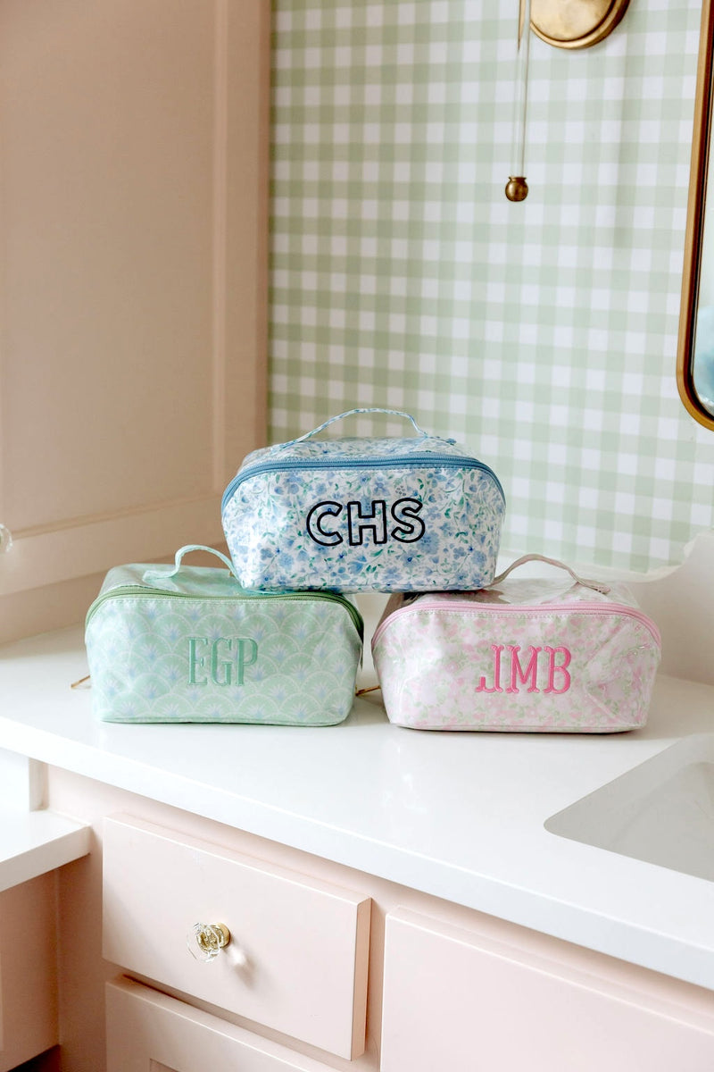 Three clear-coated flat lay pouches monogrammed CHS, EGP, and JMB in blue, green, and pink floral patterns