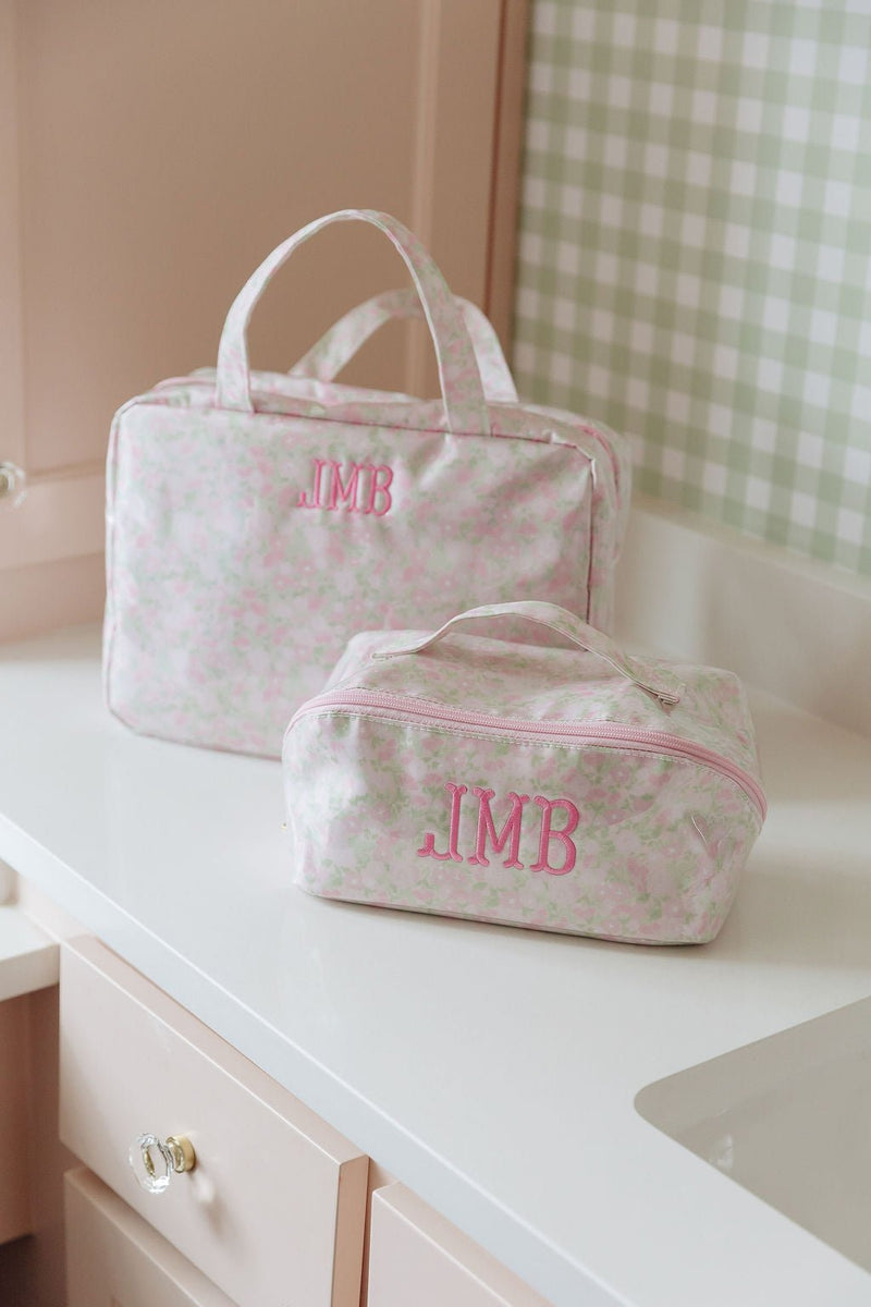 A pink floral hanging toiletry bag and matching pouch, both monogrammed 'JMB'