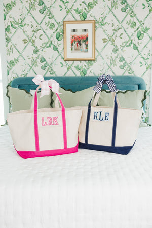 Two personalized embroidered canvas tote bags with ribbon handles.