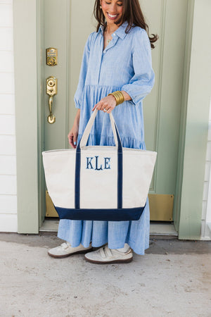 White embroidered canvas tote with navy applique initials, multipurpose use.