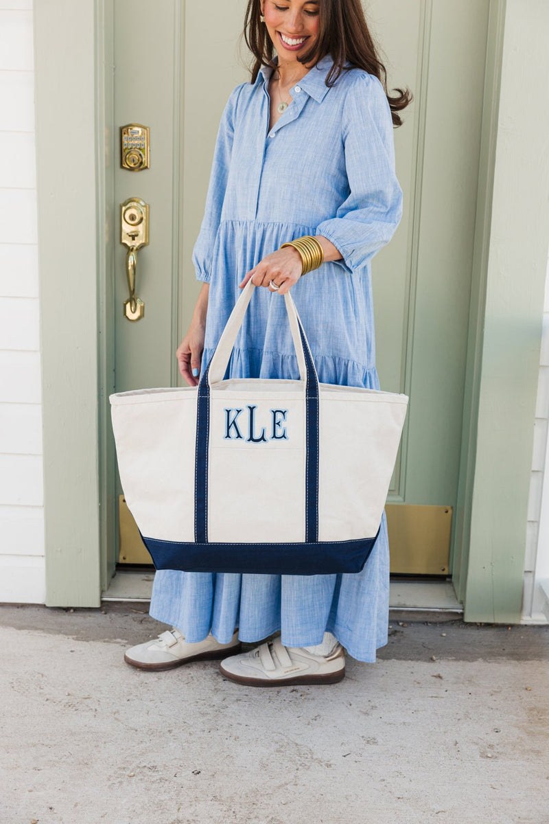 White embroidered canvas tote with navy applique initials, multipurpose use.