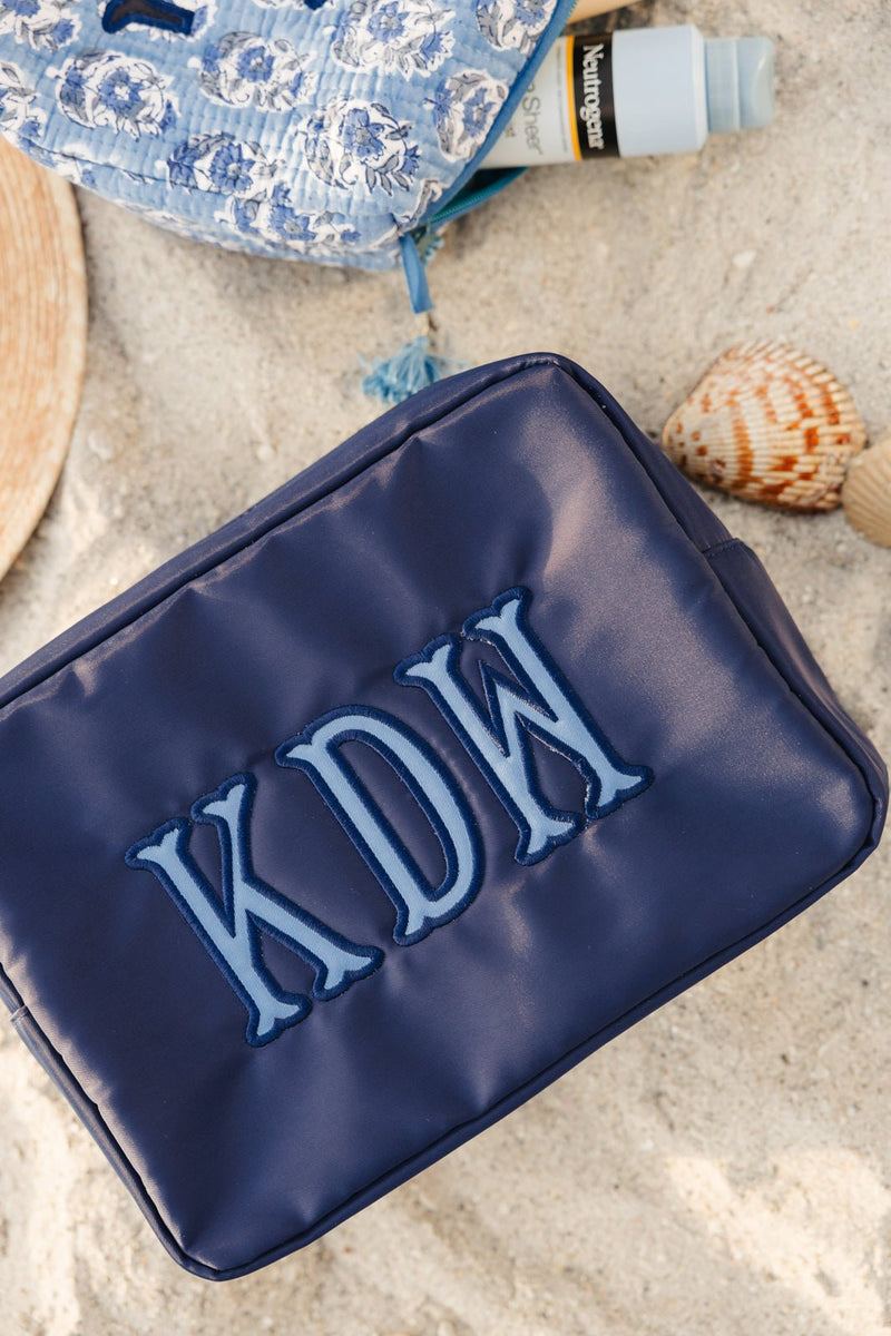 Navy nylon pouch with applique initials, stylish and spacious travel organizer.