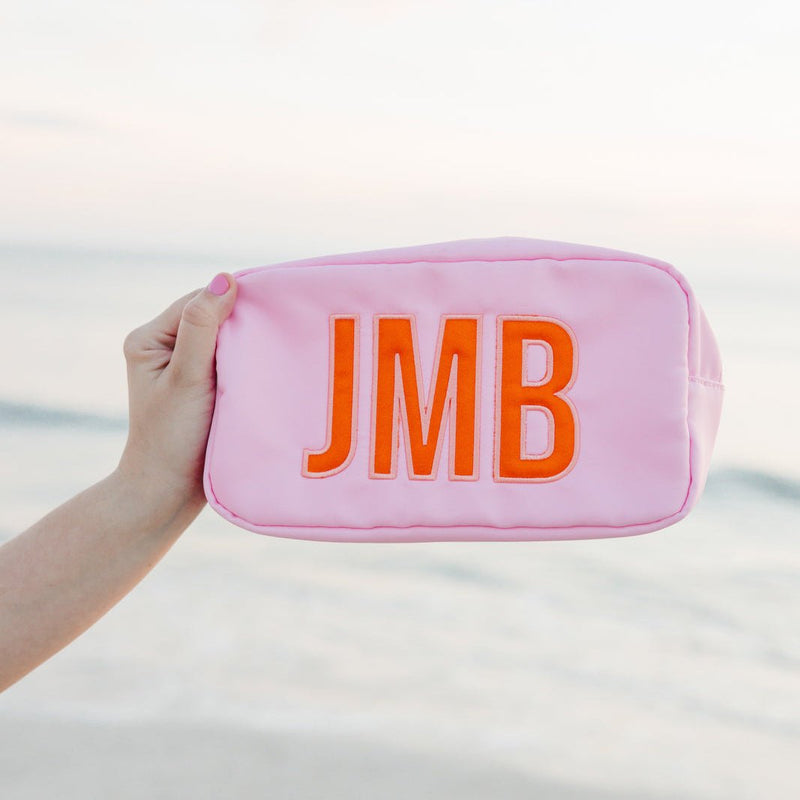Soft pink nylon pouch with applique embroidery initials JMB on bedding.