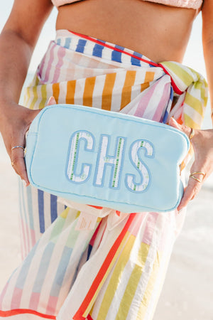 Light blue nylon pouch with applique initials displayed with makeup brushes.