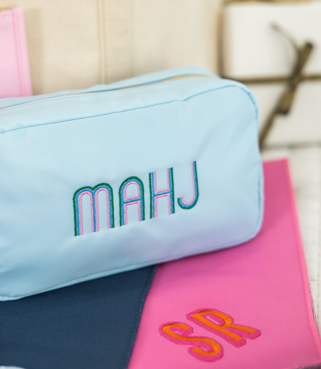 Three large, embroidered Mahjong inspired pouches in blue, white, and pink
