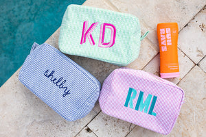 A group of seersucker pouches are customized with embroidered names and monograms in bright colors.