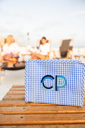 A blue roadie is placed on a table by a campfire and is embroidered with a blue monogram.