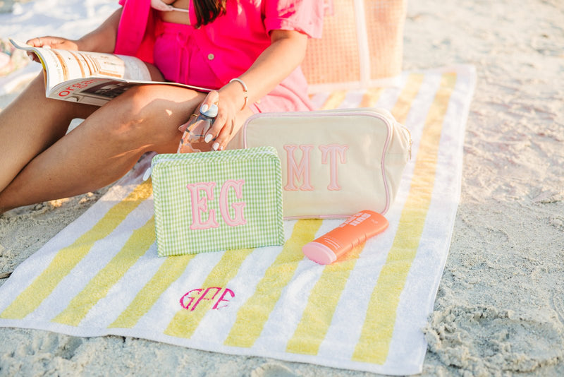 Travel-ready embroidered TRVL Roadie bag with applique monogram on pastel background.