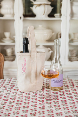 Neutral wine tote with champagne bottle, embroidered initials for a personal touch.