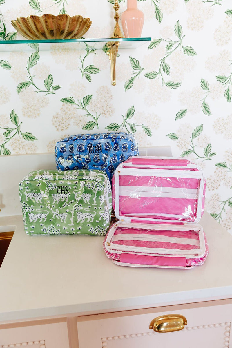 A blue floral hanging toiletry bag monogrammed 'KGB', a green leopard-print bag monogrammed 'CHS', and a pink striped open toiletry bag