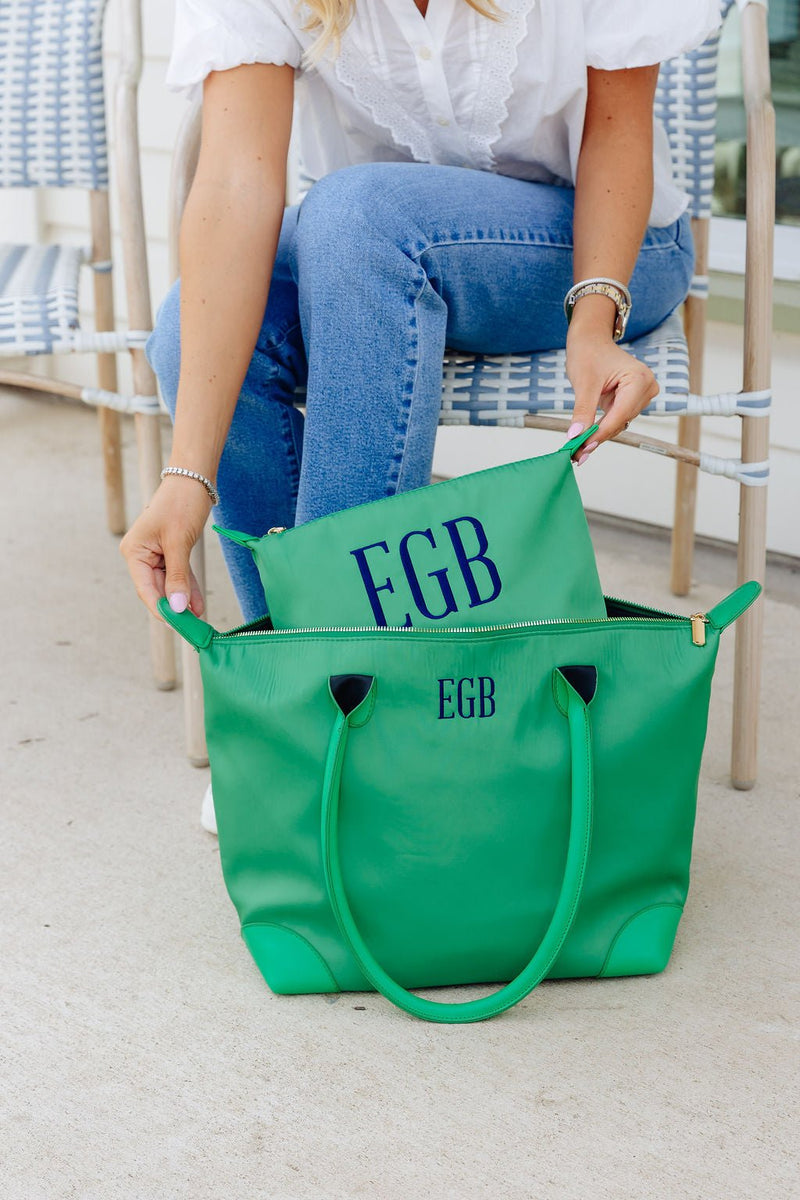 Woman zipping a green zip pouch monogrammed "EGB" in navy into a matching green tote monogrammed "EGB"