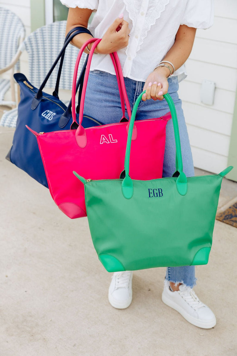 Woman carrying three totes in navy monogrammed "CHS," pink monogrammed "AL," and green monogrammed "EGB"