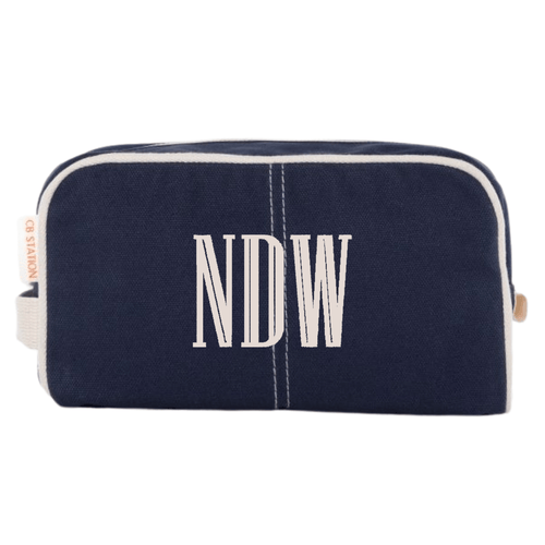A navy Personalized Canvas Travel Dopp Kit from Sprinkled with Pink, featuring a monogrammed "NDW" in elegant embroidery. Designed for both style and functionality, this durable canvas toiletry bag is accented with white piping and a sturdy zipper closure, making it the perfect addition to a custom travel essentials set. Ideal for gifting or personal use, this monogrammed dopp kit is great for organizing grooming products, cosmetics, and travel necessities in a stylish and practical way.