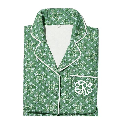 Folded green floral pajama top with white piping and a pocket monogrammed 'CRS' in white script.