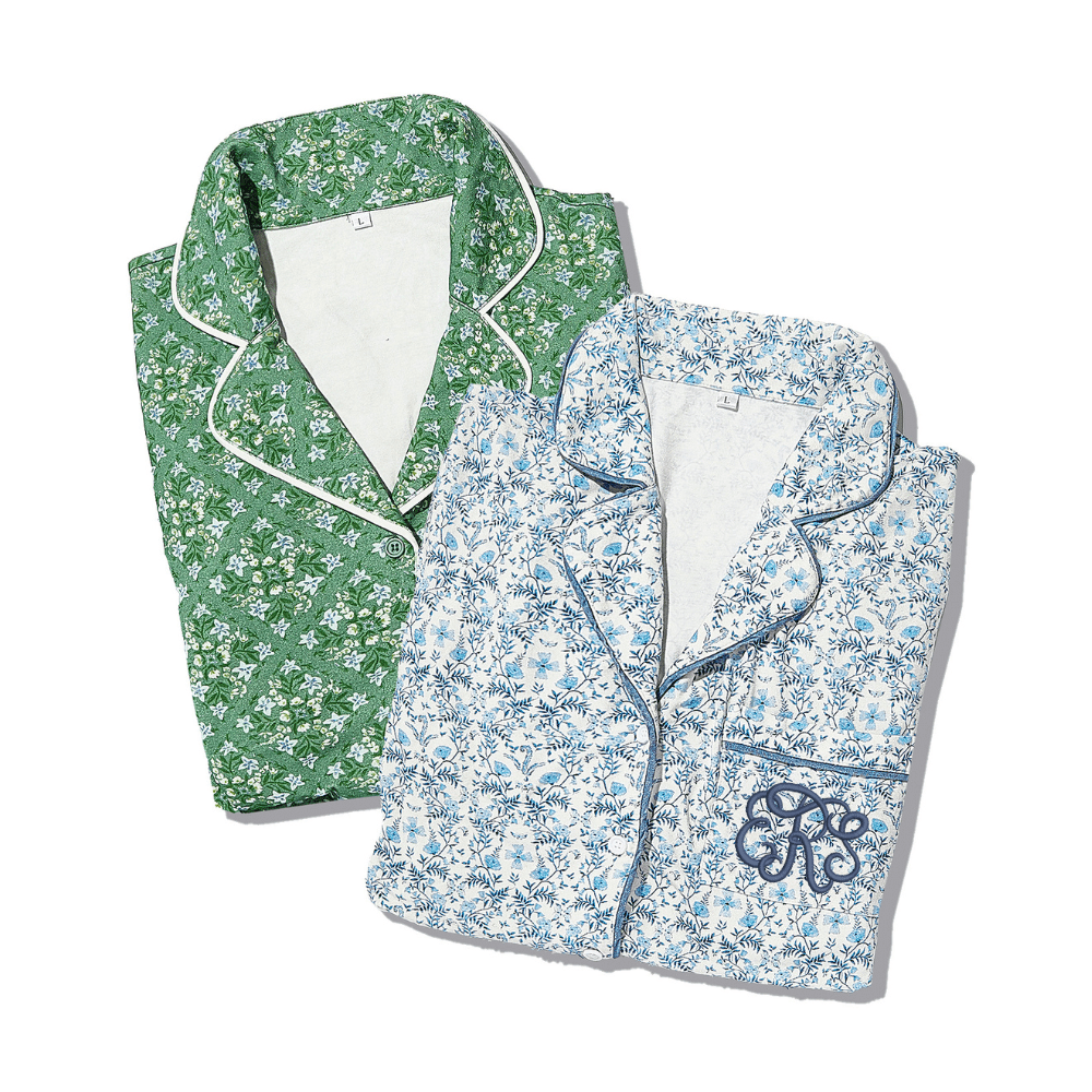 Folded green floral pajama set with white trim and folded blue floral pajama set with navy trim.