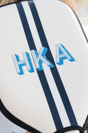A navy and white paddle cover is customized with a light blue embroidered monogram
