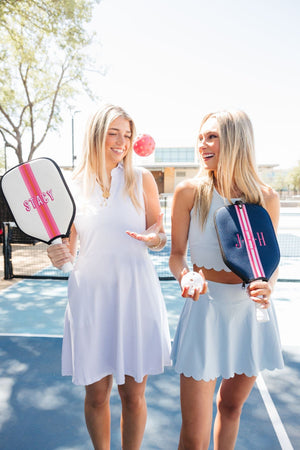 Two girls on a pickleball court hold paddles in customized covers