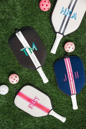 A group of pickleball paddle covers are laid out with different customizations in fun colors.