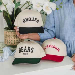 Stack of personalized trucker hat with embroidered text, perfect for grads and everyday wear.