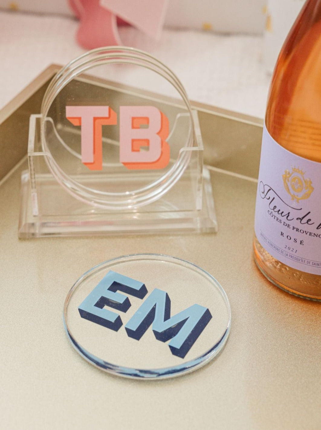 A set of coasters sits in a holder showing off it's custom pink monogram.