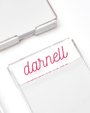 Clear acrylic notepad holder with pen, styled on a white desk surface