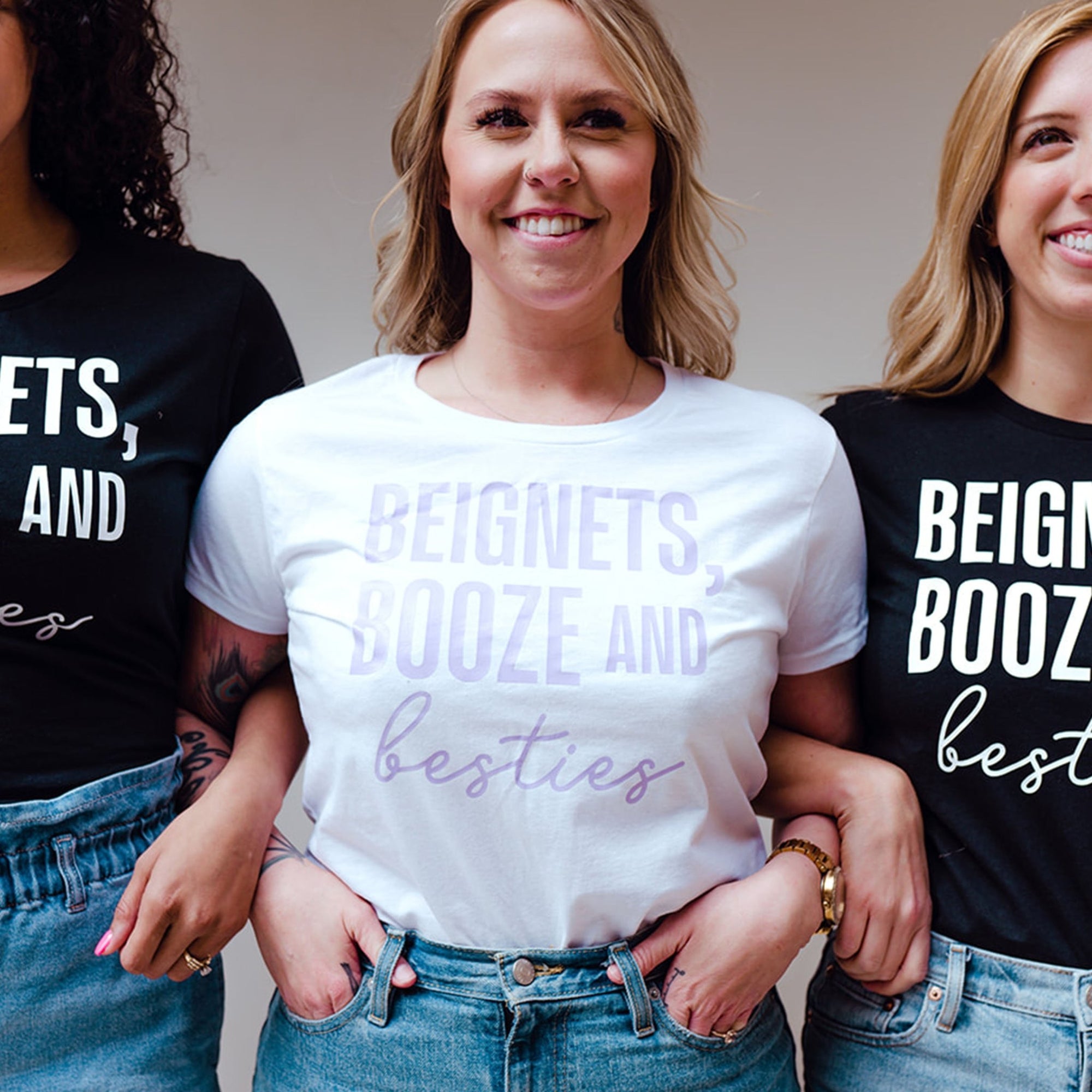 A black and a white t shirt are customized with a purple "Beignets, Booze and Besties" designs