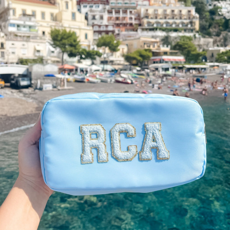 A blue nylon pouch with white patches is held up in front of the water 