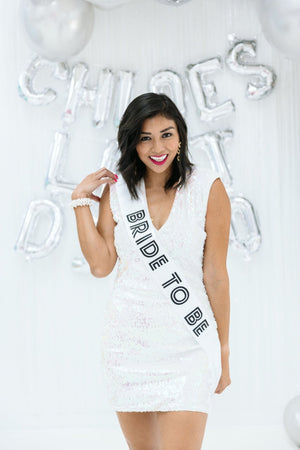 A woman in white wears a "Bride To Be" sash