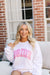 A white sweatshirt with "Bride" written on the front in pink and a white sweatshirt with "Wifey" written on the front in blue