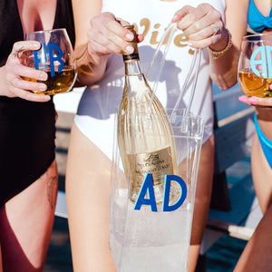 A woman puts a bottle of wine into a clear wine bag with a blue monogram.