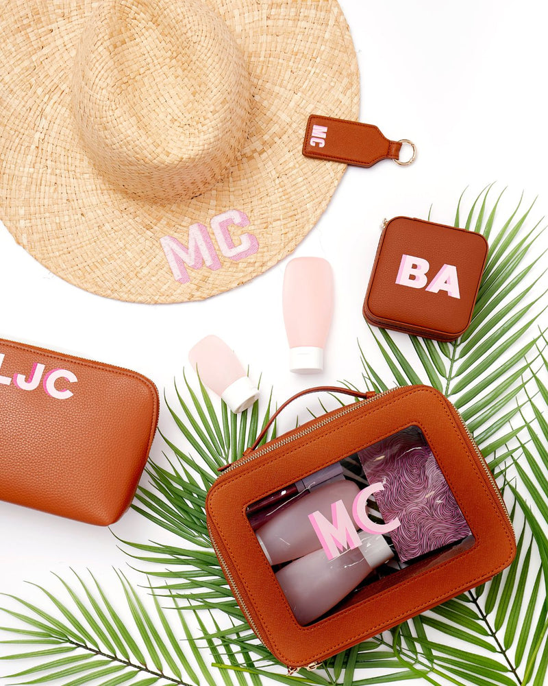 An array of leather products are customized with matching pink monograms.