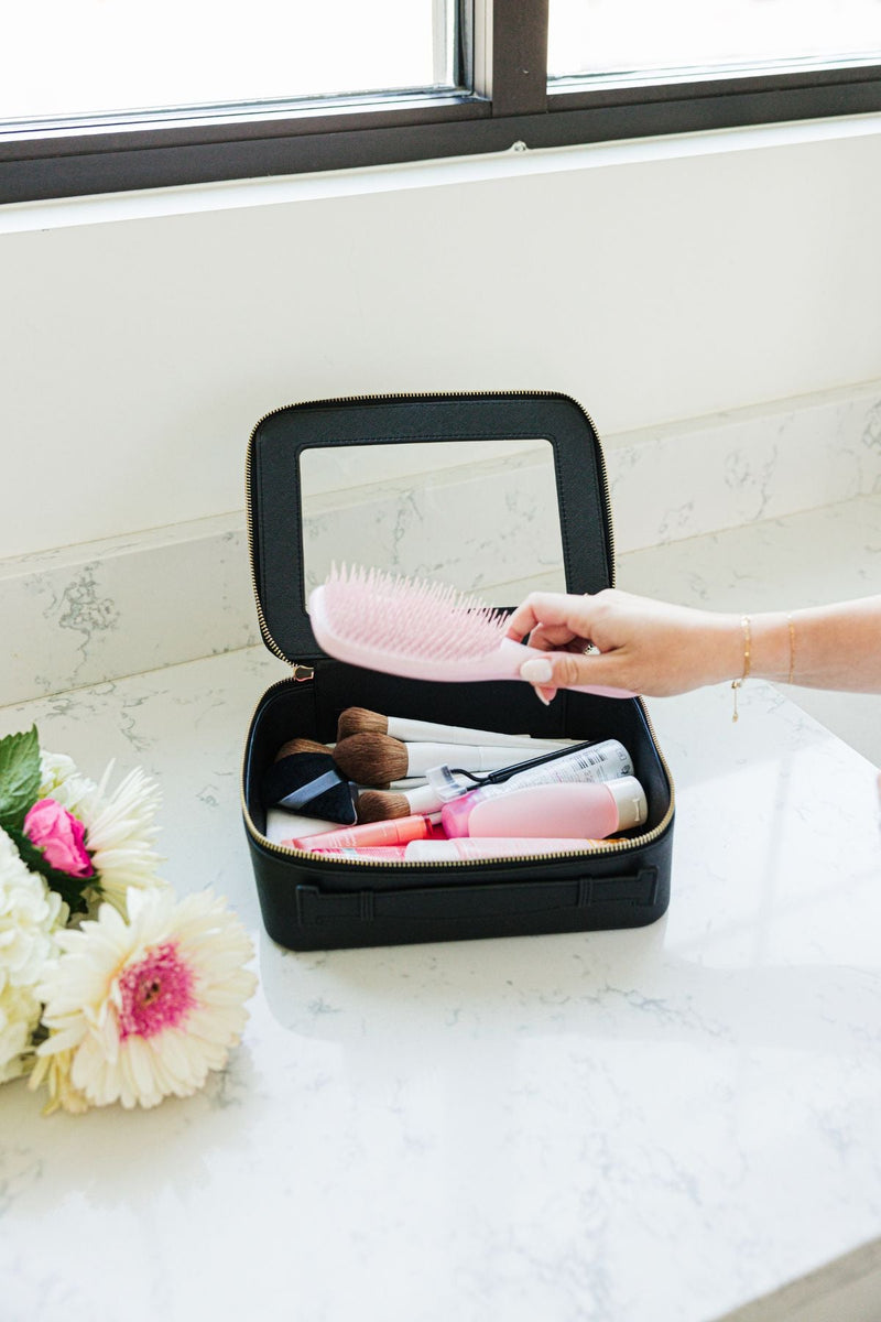 A person reaches into their black clear case full of toiletries.