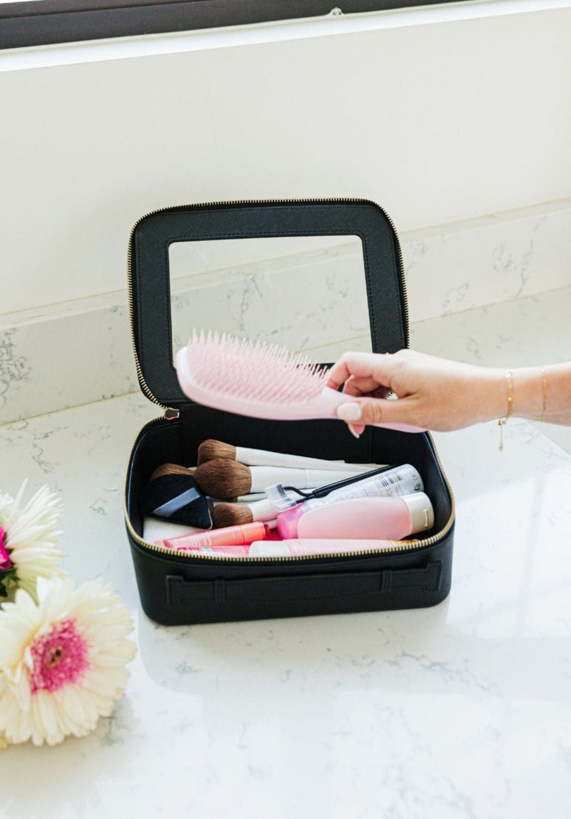 A person reaches into their black clear case full of toiletries.