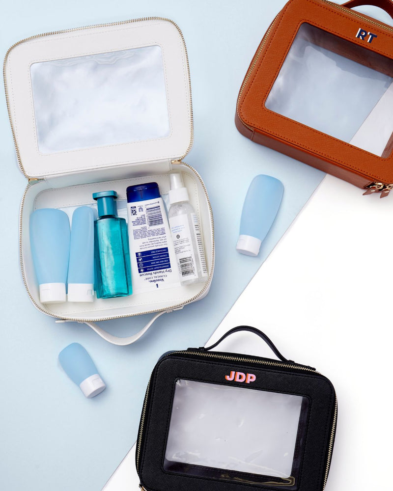 A group of white, tan, and black train cases are personalized with colorful monograms.