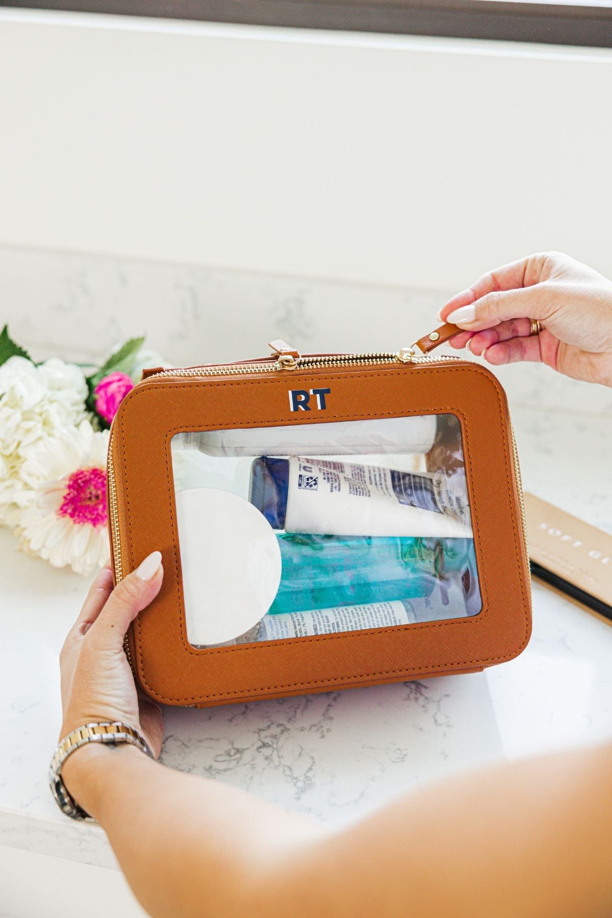 A group of white, tan, and black train cases are personalized with colorful monograms.