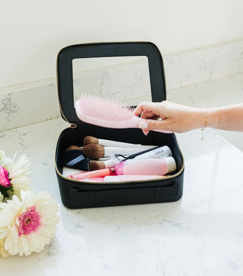 A person reaches into their black clear case full of toiletries.