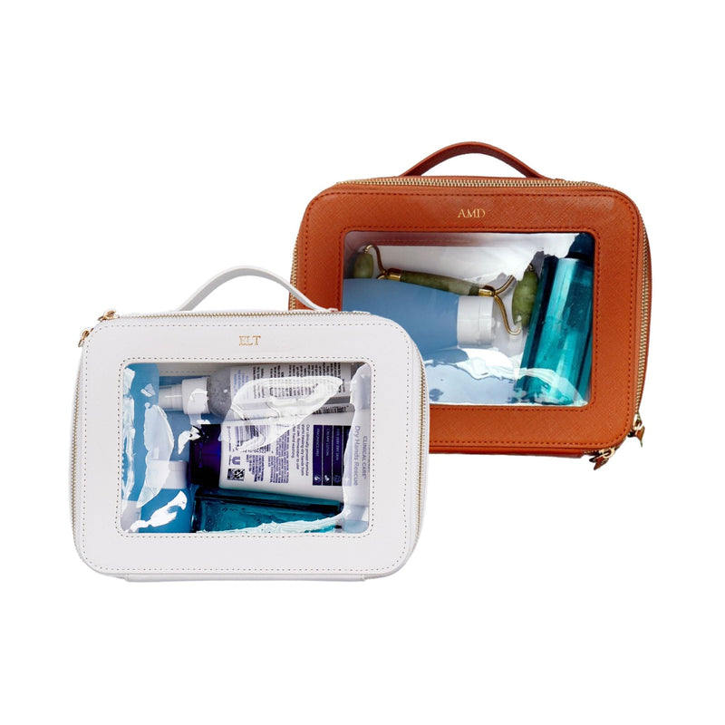 A white and tan train cases are personalized with gold foil monograms.