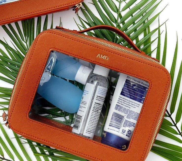 A tan leather toiletry case is monogrammed with gold letters.