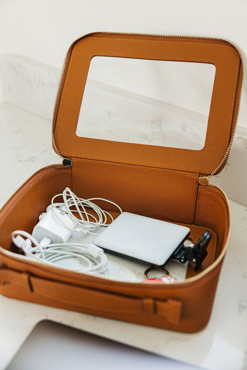 A tan leather case is filled with cords and headphones.