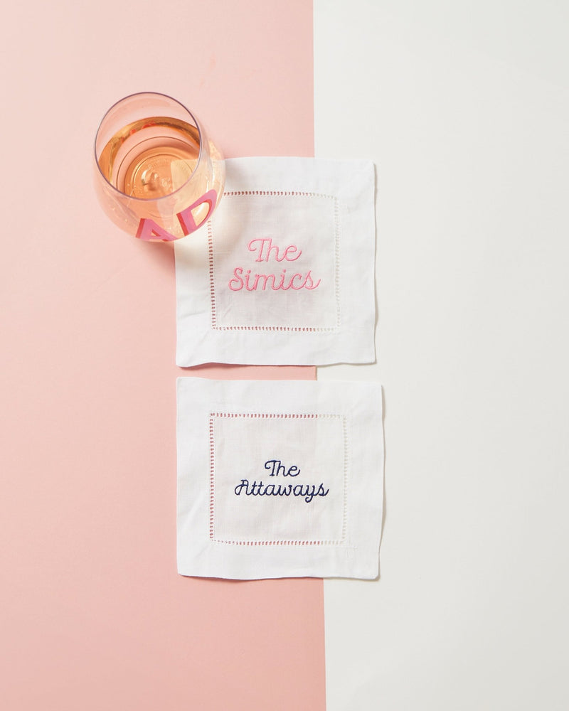 Two cocktail napkins are set out with a wine glass to show off their custom embroidered names.