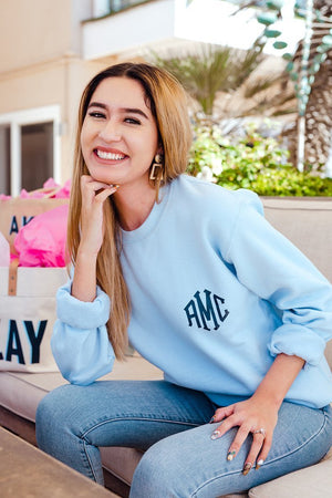 A woman wears a customized blue sweatshirt with her monogram.