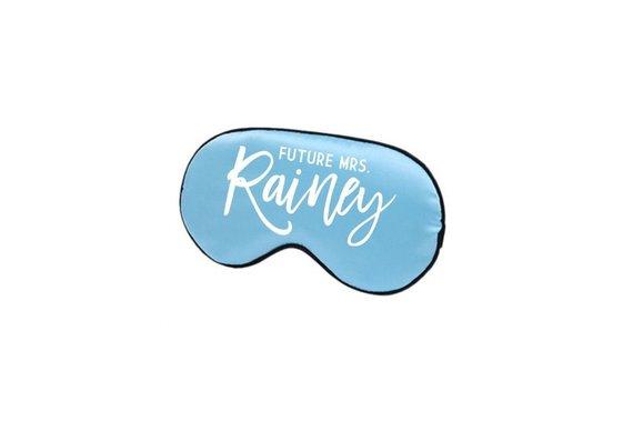 A sleep mask is customized to read "Future Mrs. Simic" in a light blue font.