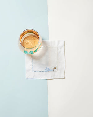 An embroidered cocktail napkin with a last name and two wine glass motifs.