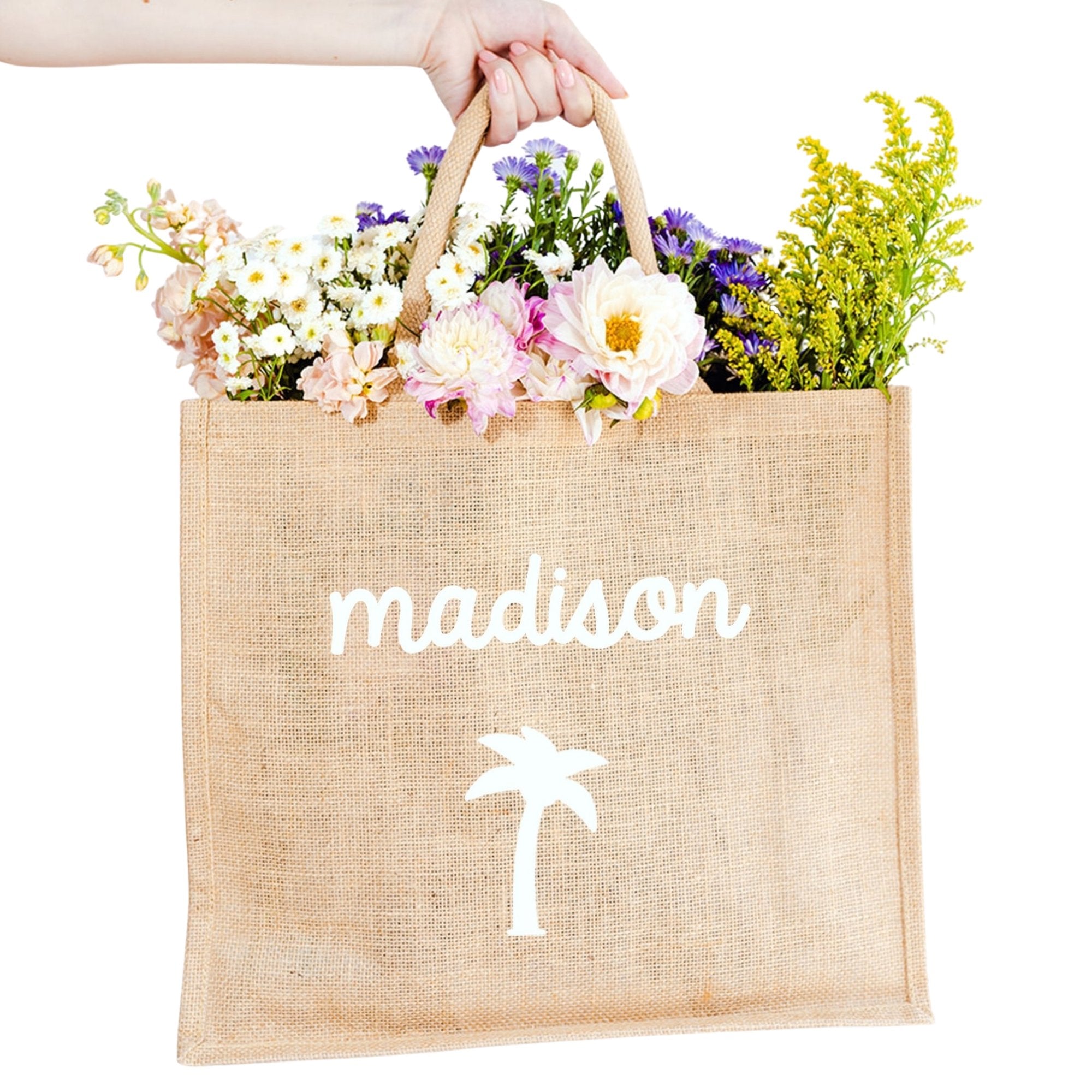 A custom jute bag reads "Madison" on the front in cursive with a palm tree icon