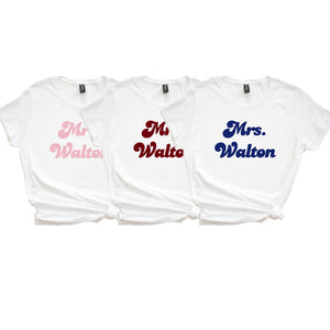 3 white shirts are customized with "Mrs. Walton" in different colors.